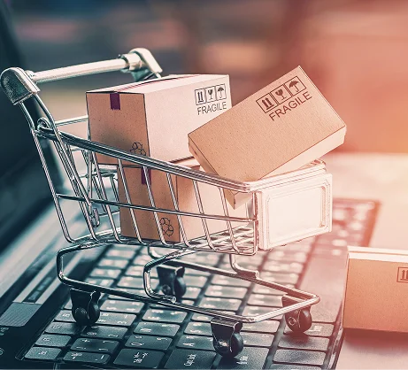 Mini shopping cart filled with small cardboard boxes on a laptop keyboard.